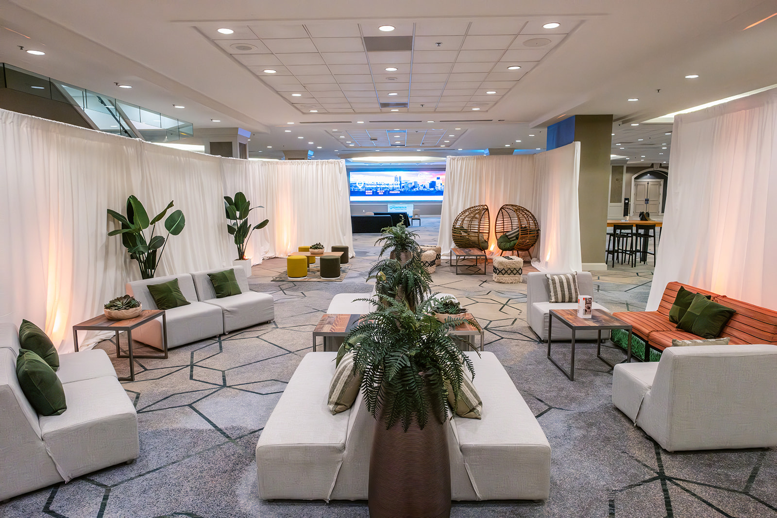 Photo of CORT Lounge and Experience 2024 featuring earth toned white and green furniture with wood accents and green plants